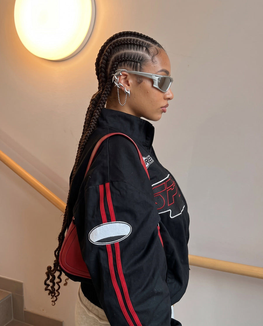 Braids and a track jacket on a stairwell landing, wearing the Saber Ear Cuff