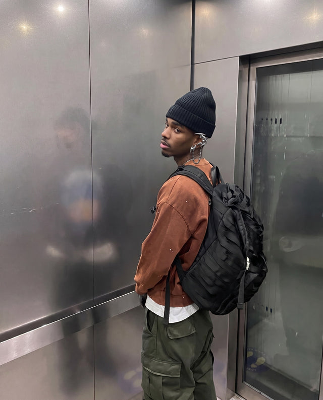 Beanie and backpack in a steel lift, wearing the Saber Ear Cuff