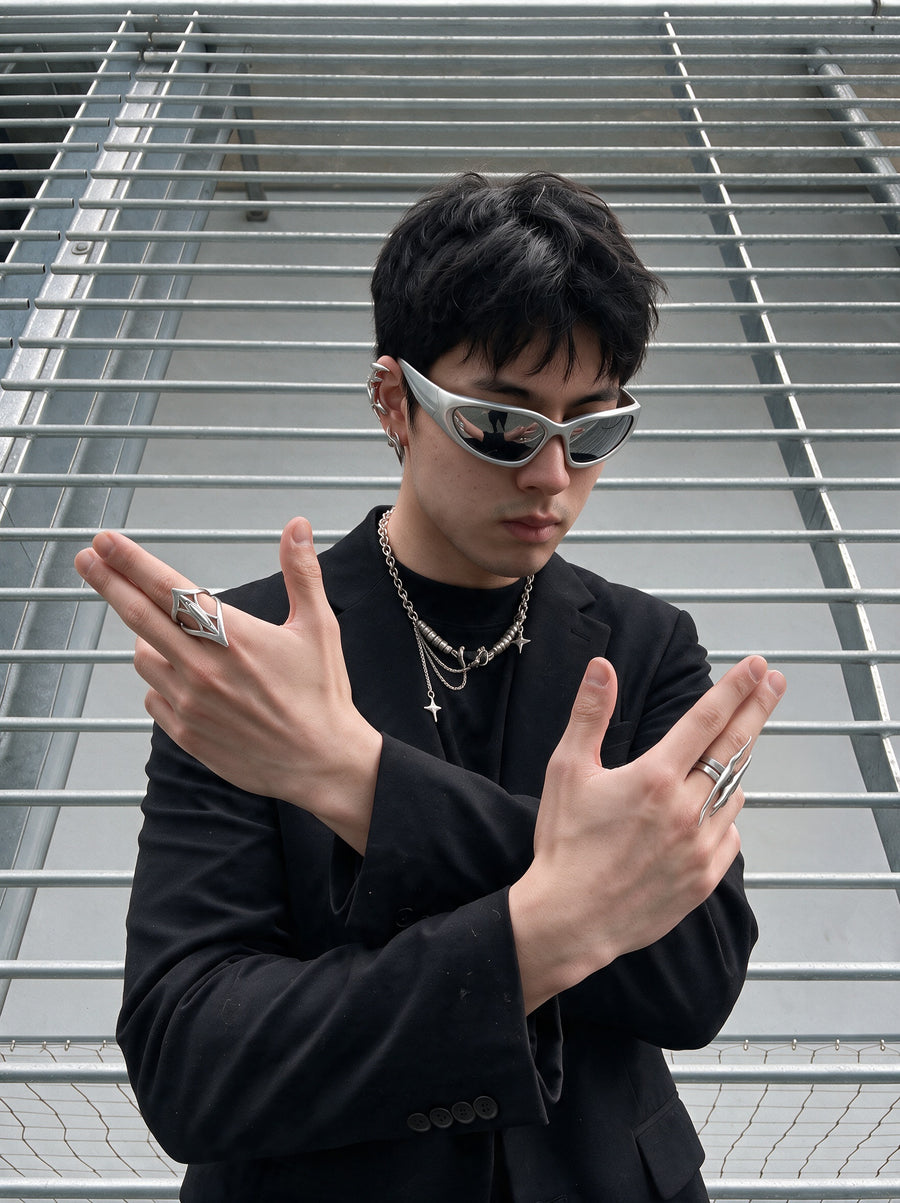 Arms crossed in a steel stairwell, wearing the Anarchy Necklace